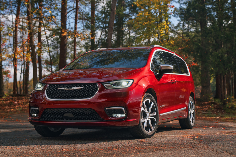 2026 Chrysler Pacifica in red parked among autumn trees, showcasing sleek design and premium exterior finishes