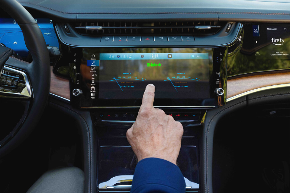 Close-up of the Grand Cherokee touchscreen as a driver taps the McIntosh audio interface