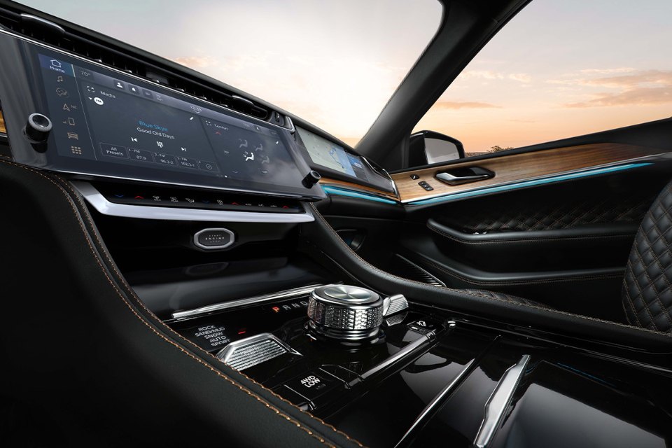 Angled view of the Grand Cherokee dash and center console with large display and rotary shifter